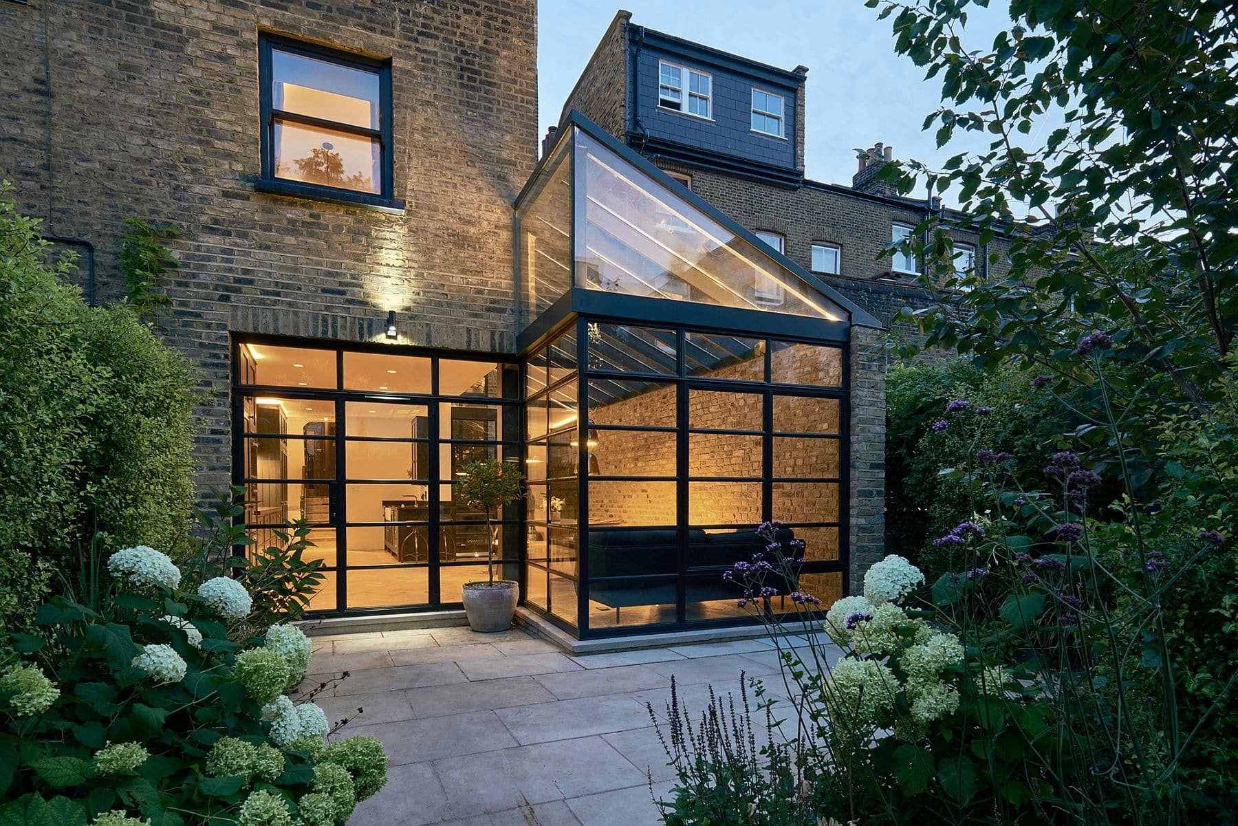 Contemporary crittall glass extension illuminated at dusk